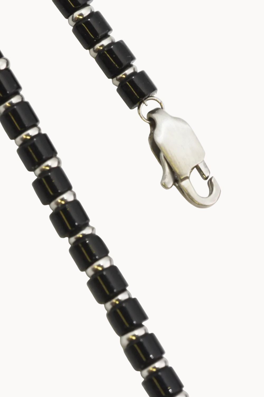 Black beaded necklace with silver clasp on a white background