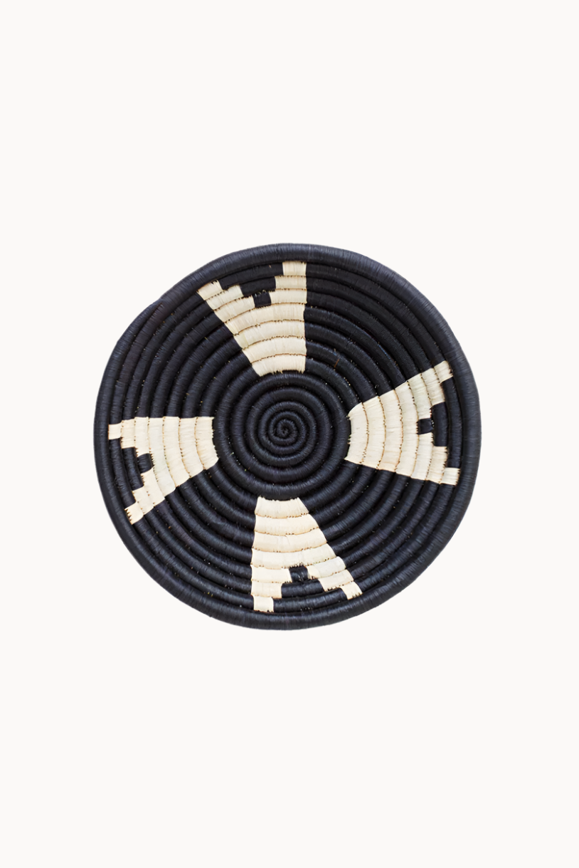 Round woven basket with black and beige pattern on a white background