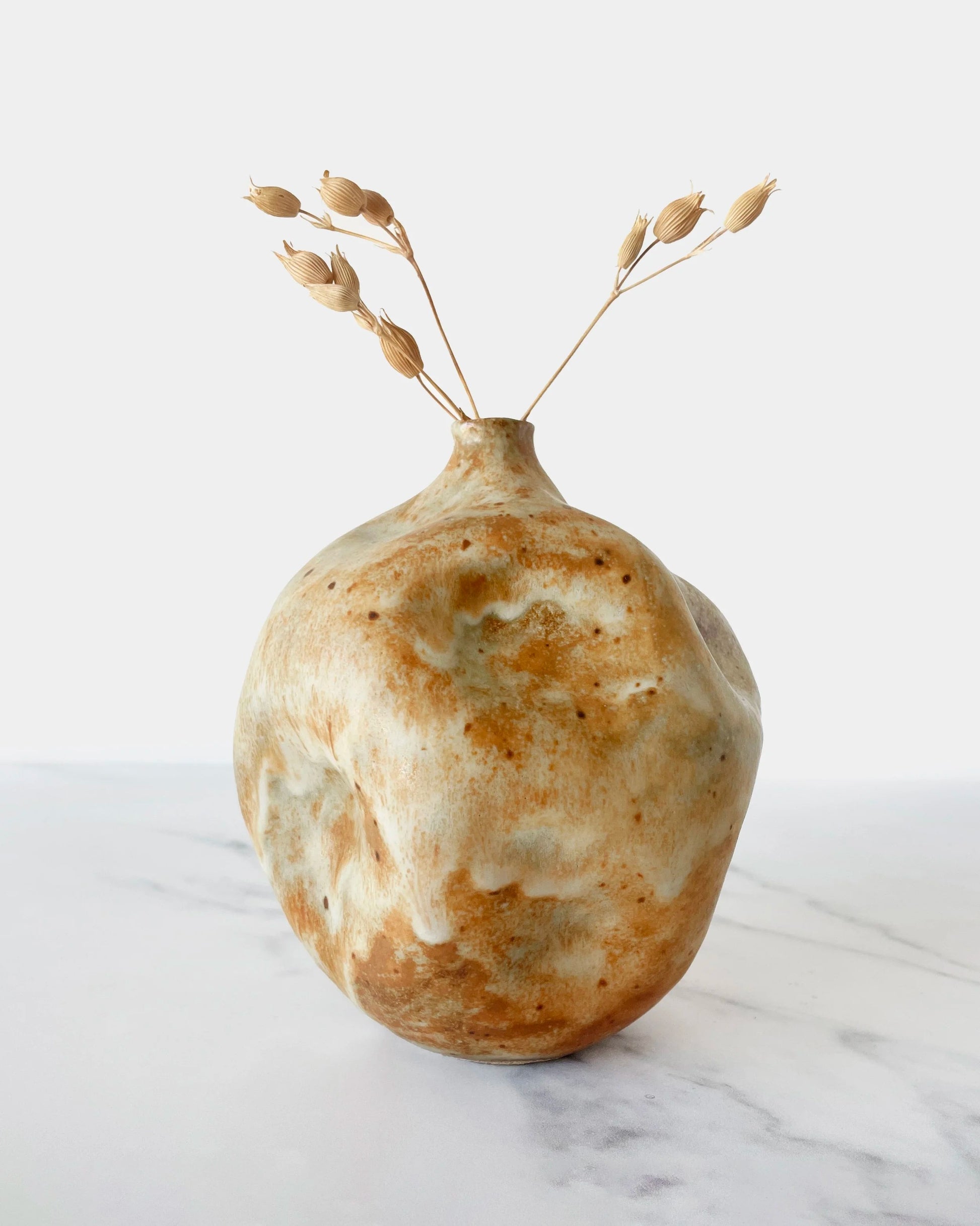 Decorative ceramic vase with a natural clay-colored finish on a marble surface