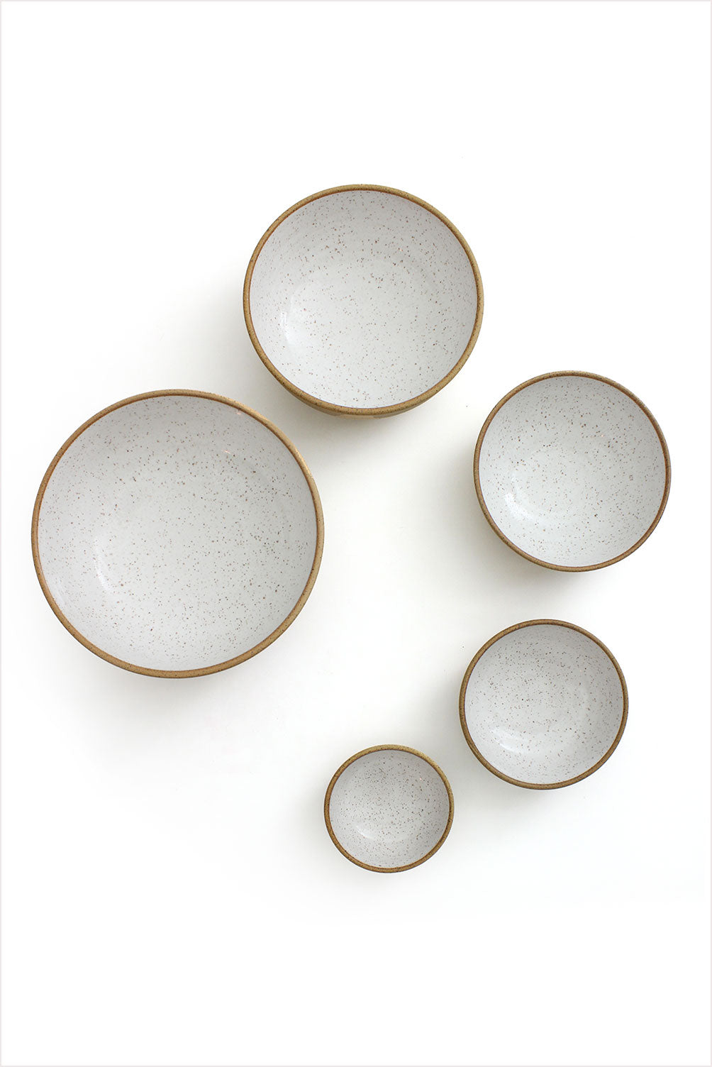 Five white ceramic nesting bowls with a speckled pattern, displayed in descending size order with the smallest on the top and the largest at the bottom.