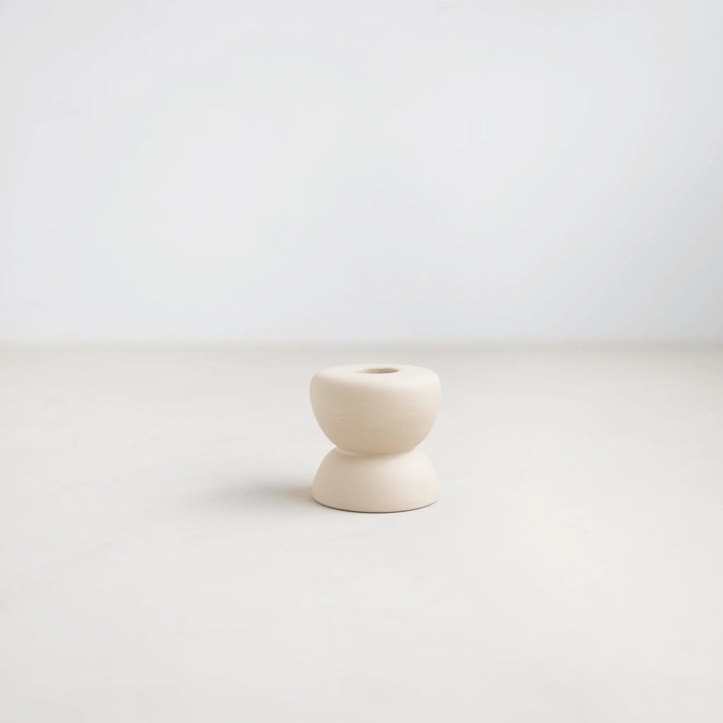 White ceramic candle holder on a light gray background