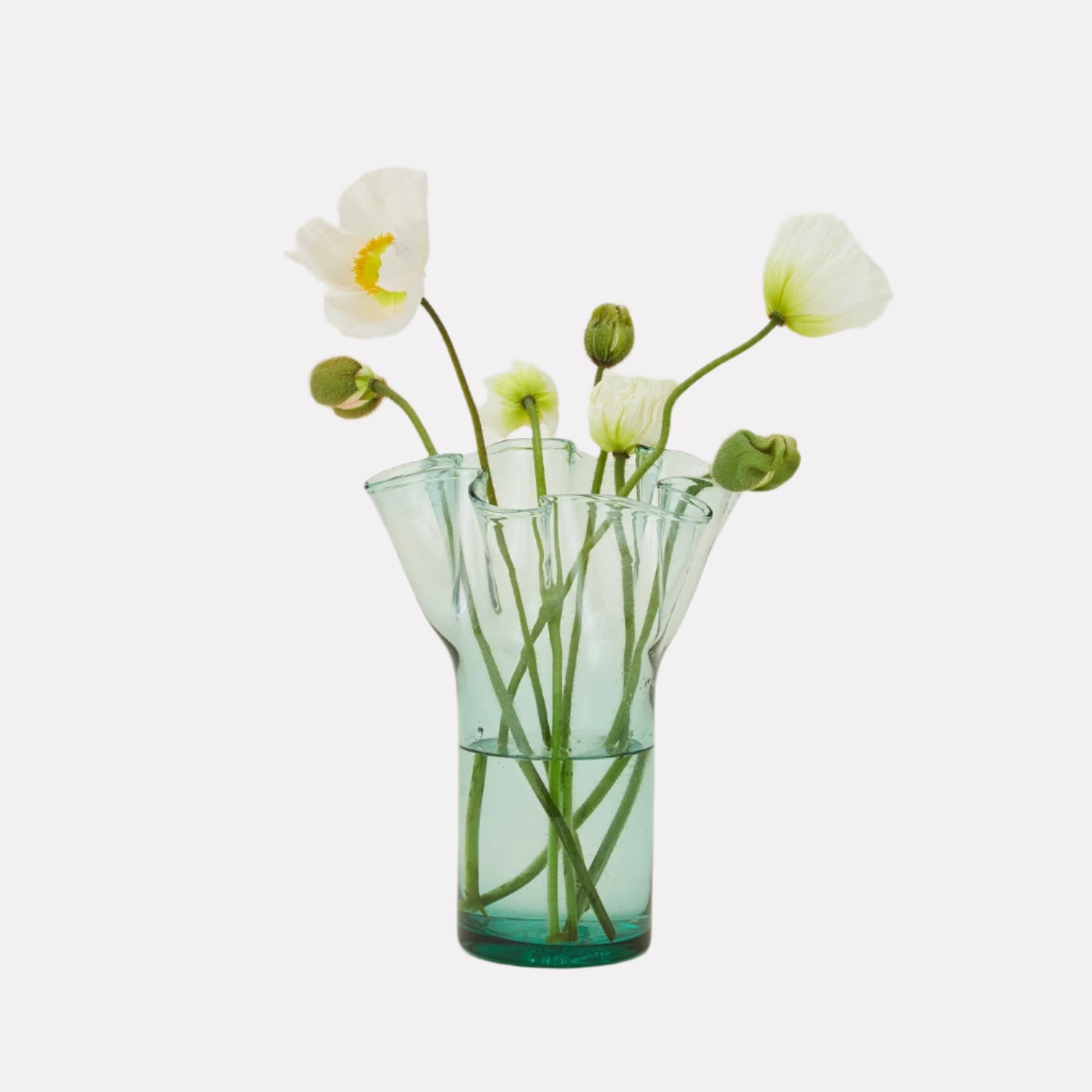 A handcrafted green glass vase with a unique shape, featuring several white flowers arranged in it.