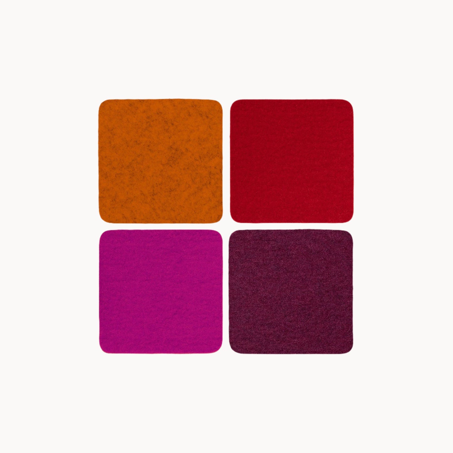 Four square wool felt coasters in orange, red, pink, and purple on a white background