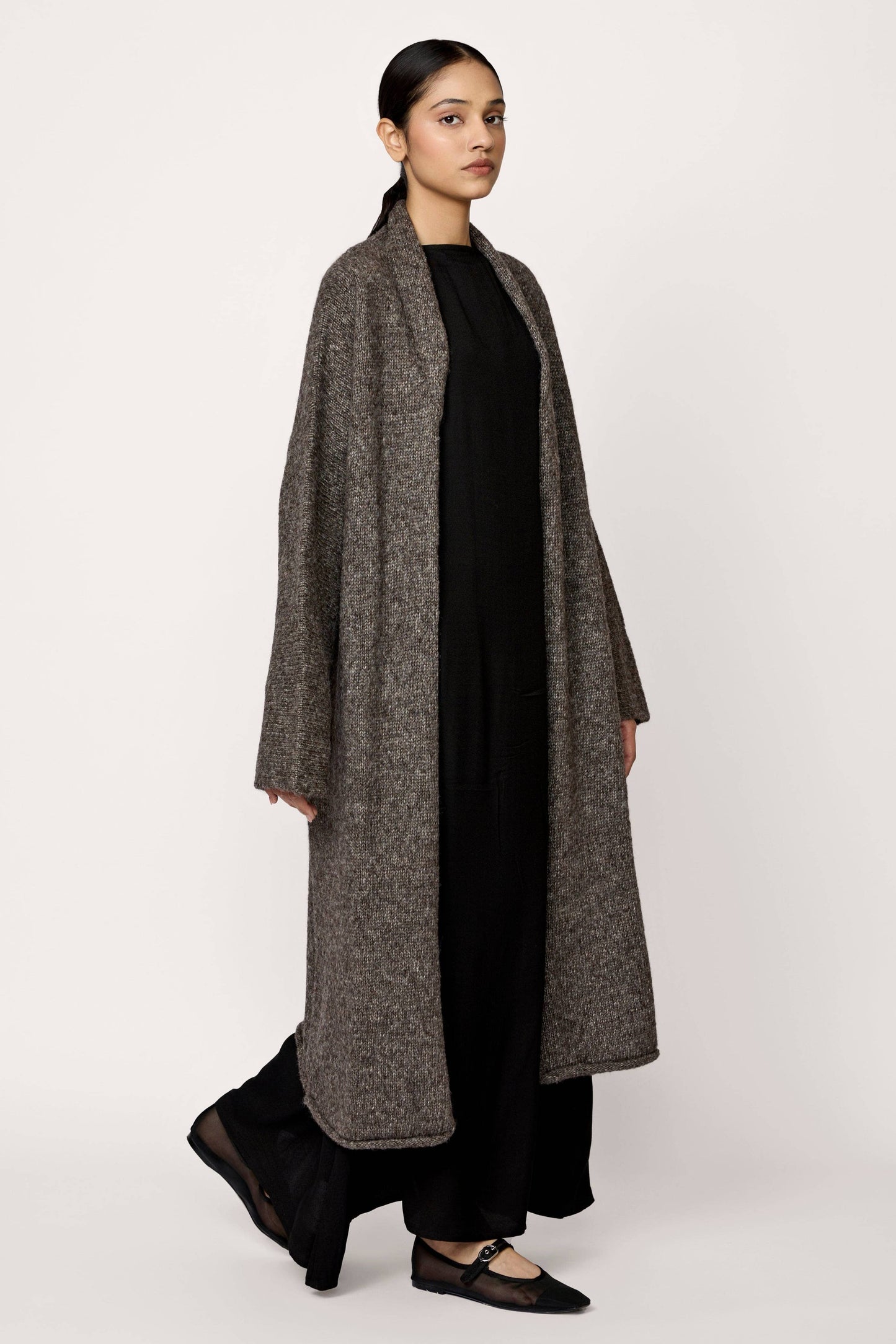 Woman wearing a long gray coat on a white background