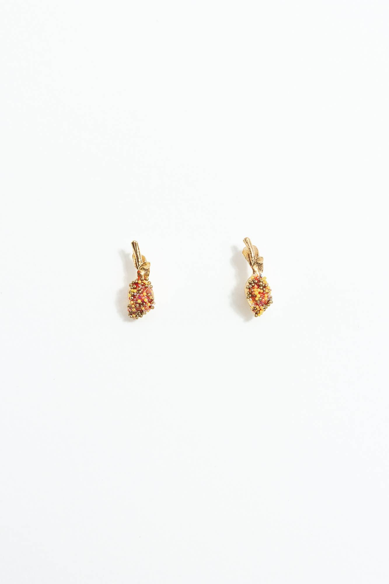 Pair of gold lemon-shaped stud earrings with red and yellow beading on a white background