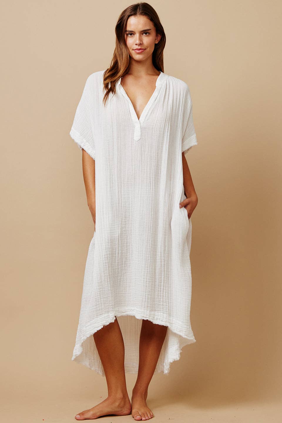 Woman wearing a white cover-up dress against a beige background