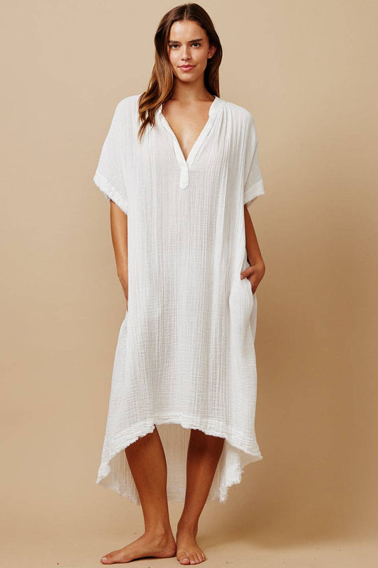 Woman wearing a white cover-up dress against a beige background