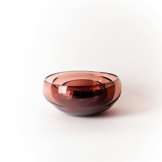Three nesting rose colored glass bowl on a white background