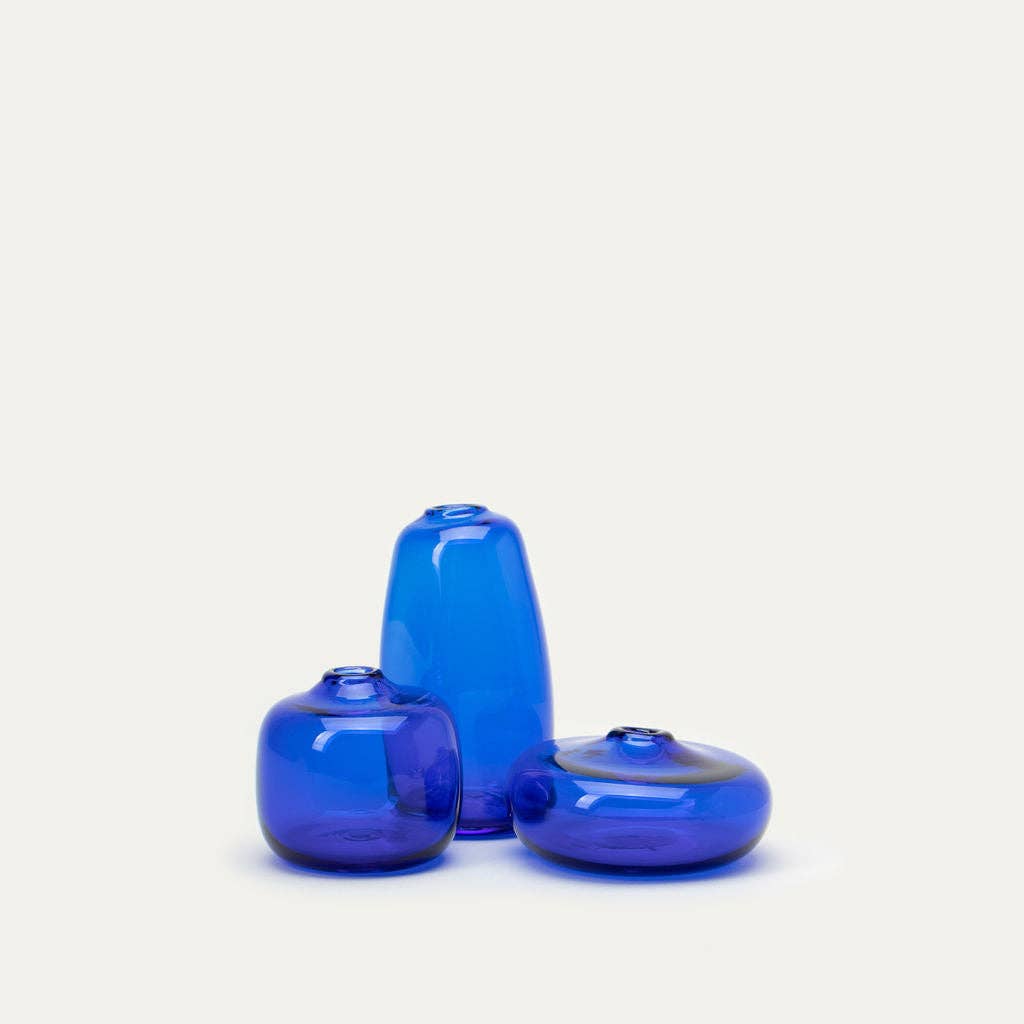 Three blue glass vases of different shapes on a light gray background