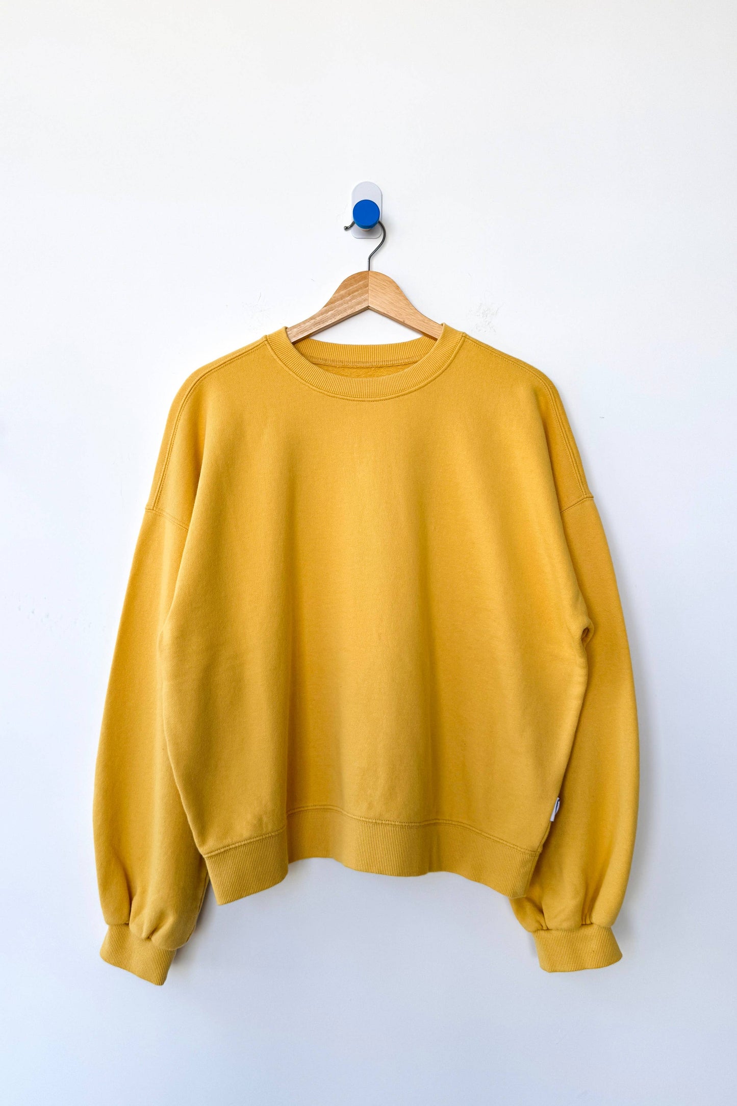 Yellow sweatshirt on a hanger against a white background
