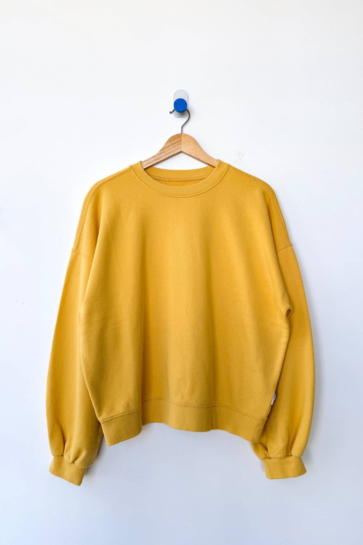 Yellow sweatshirt on a hanger against a white background