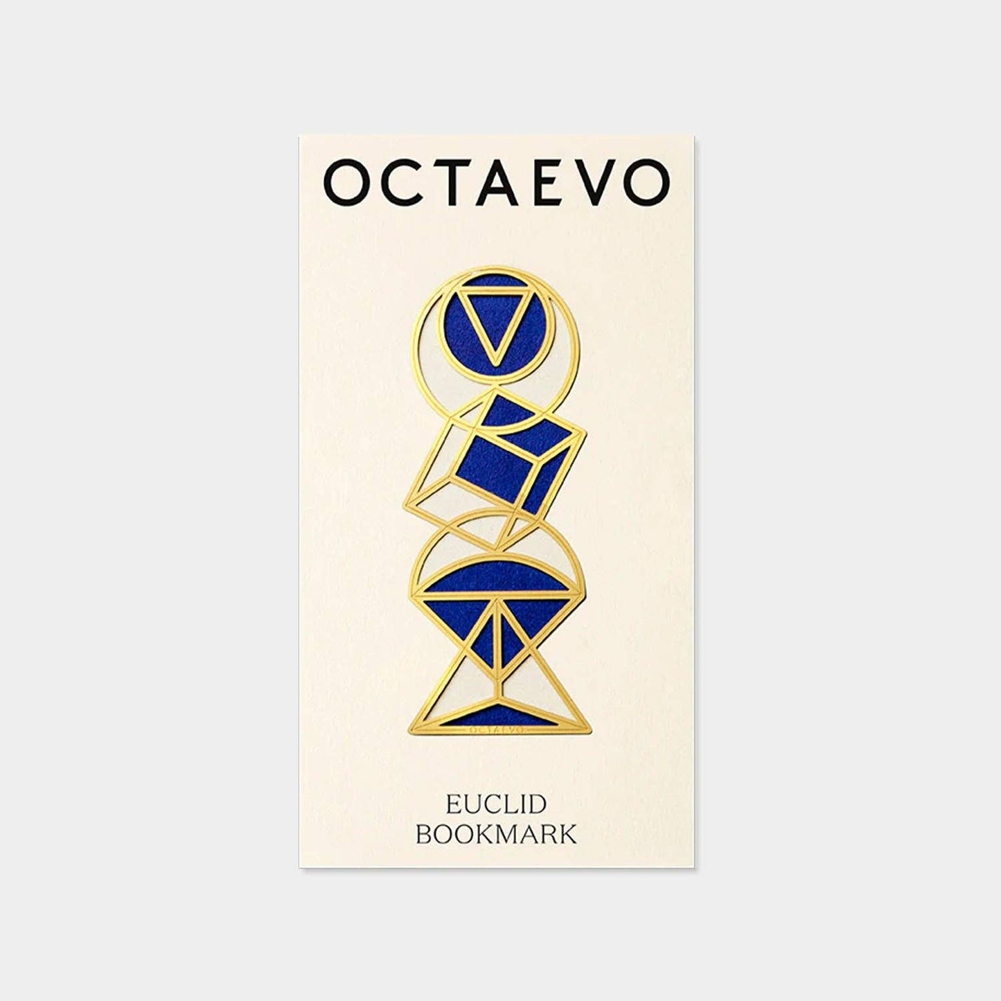 A brass bookmark with a geometric design, featuring a triangle and a circle, presented on a post-card sized mount with the text 'OCIAEURO' and 'EUCLID BOOKMARK'.