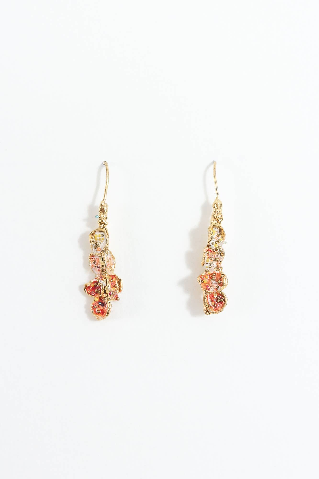 Pair of red, soft pink, and white earrings set in brass and displayed on a white background