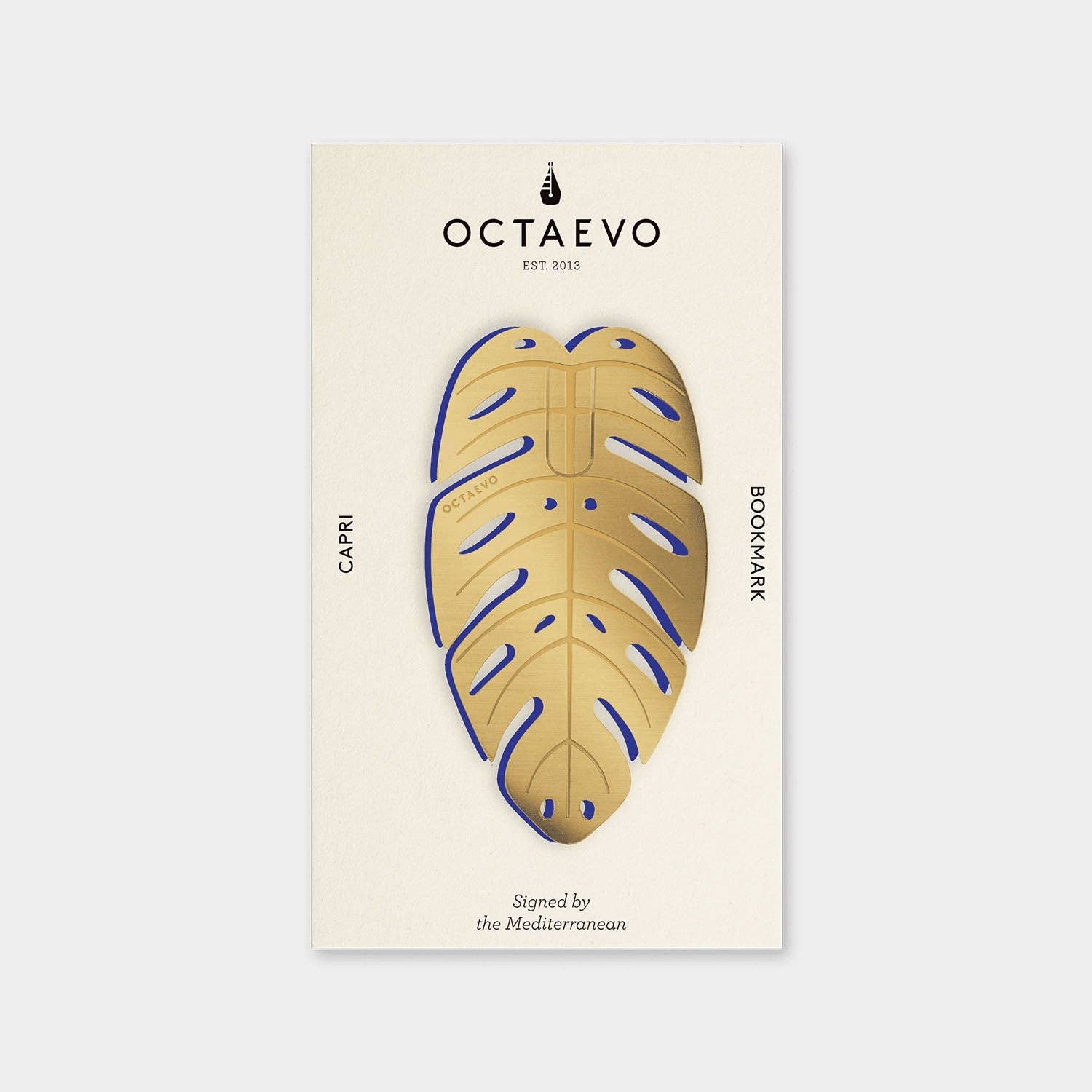 A brass bookmark with a leaf design, finished with a subtle sheen, displayed on a post-card sized mount with the text 'OCTAEVO' and 'CAPRI'.