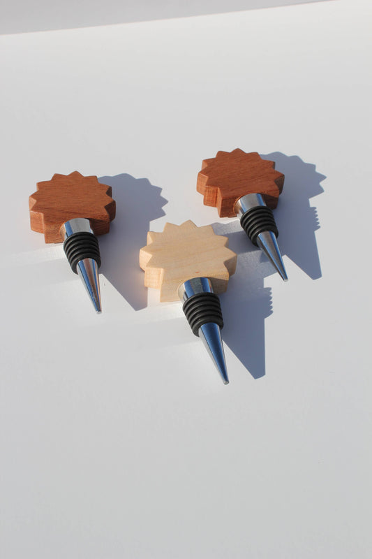 Three sunburst-shaped wooden wine bottle stoppers on white background