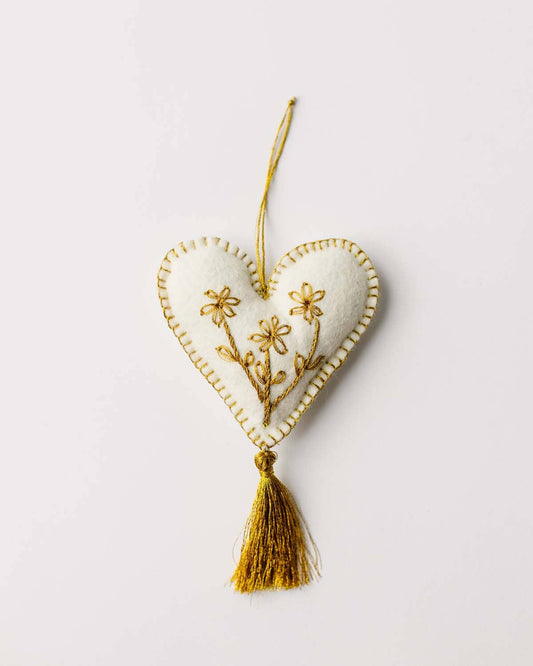 Heart-shaped ornament with floral embroidery and a tassel on a light background