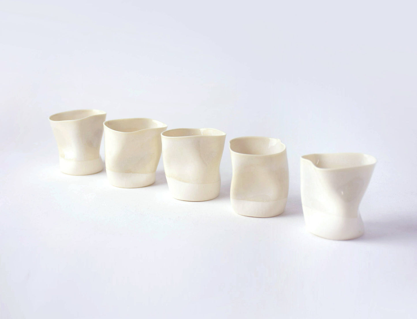 Set of five white ceramic cups on a light gray background