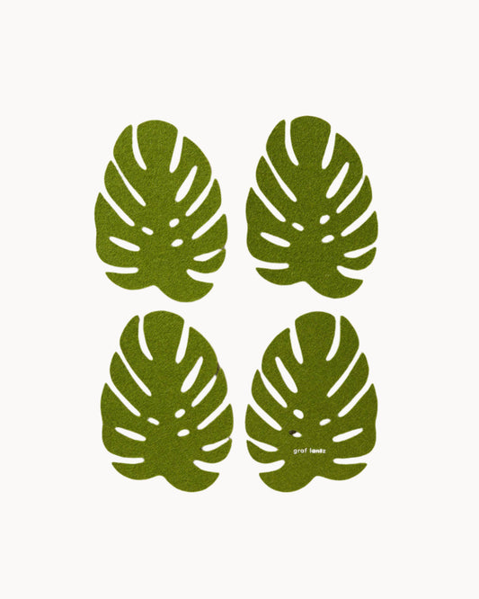 Four green leaf-shaped wool felt coasters on a light gray background