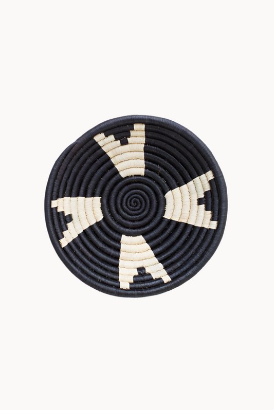 Round woven basket with black and beige pattern on a white background