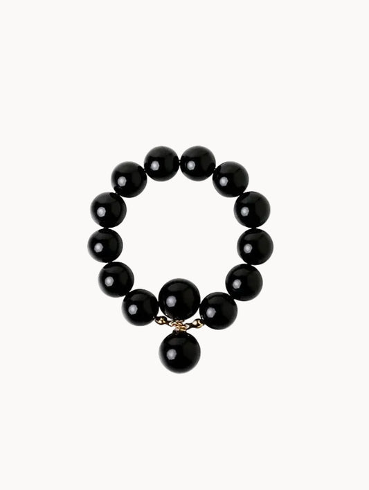 Black beaded bracelet with a gold charm on a white background