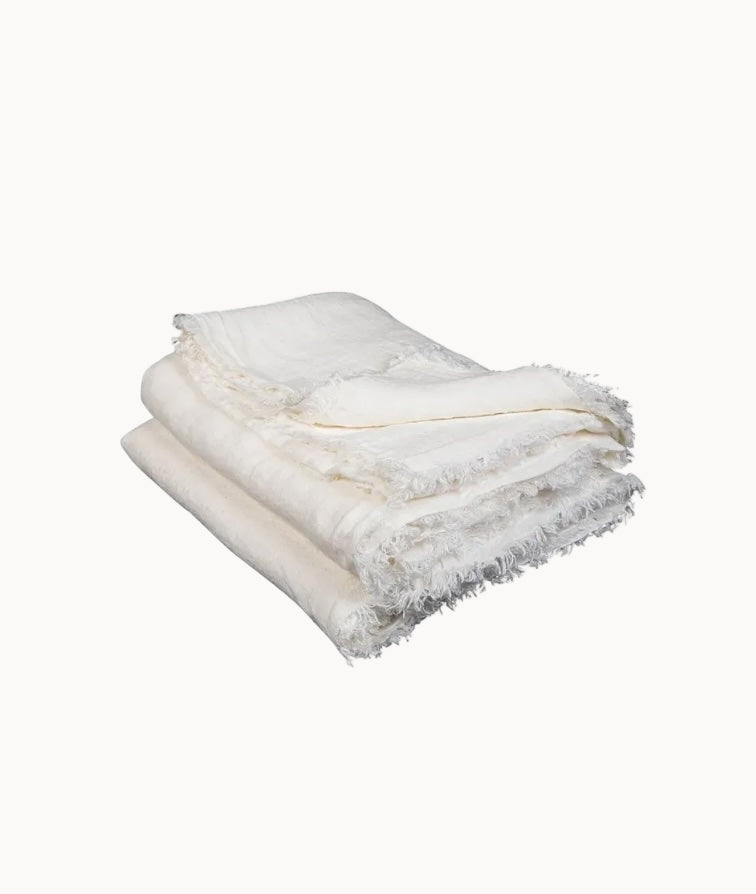 Ivory fringed throw blanket on a white background