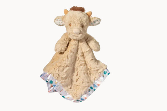 Beige cow plush toy with a patterned blanket on a white background