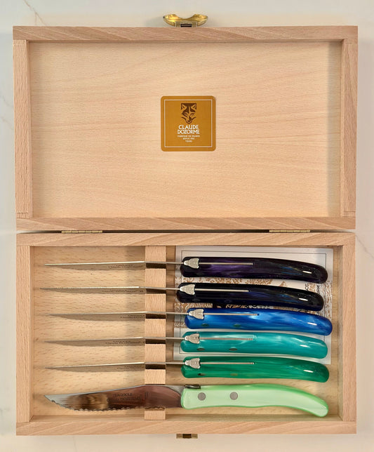 Set of knives with colored handles in a wooden box
