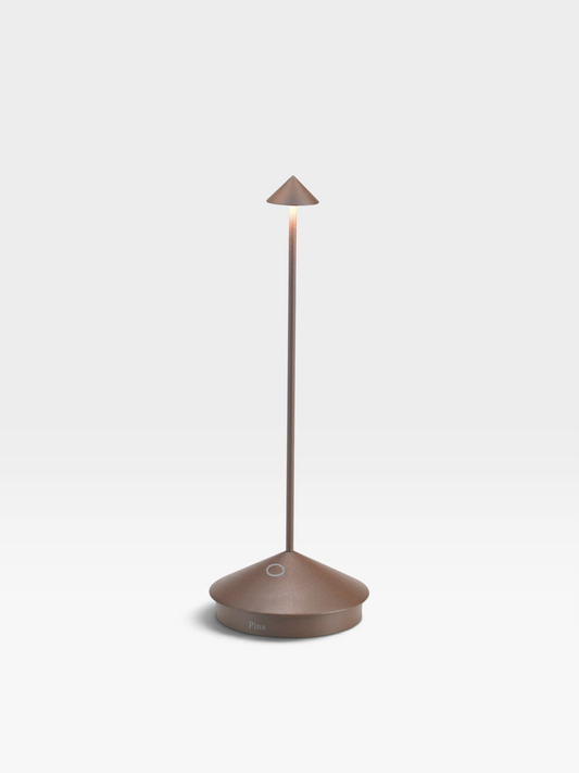 A rust colored metal table lamp with a round base, long, slender neck and small, conical shade.