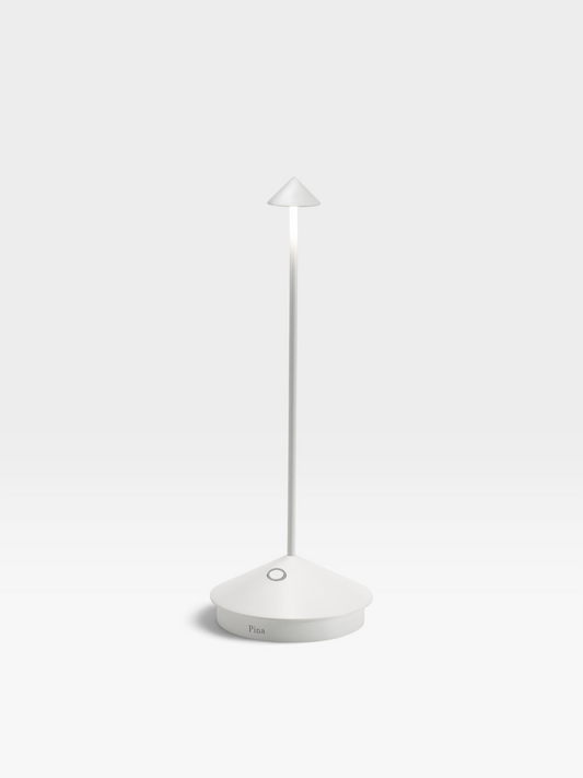 A white colored metal table lamp with a round base, long, slender neck and small, conical shade.