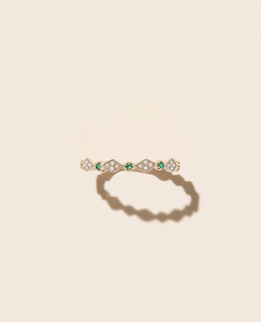 Gold, diamond, and emerald thin ring with diamond-shaped motif shown from front view against an off-white background