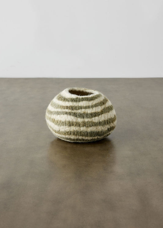 An ivory wool decorative bowl with olive green stripes sits on a wooden surface with a white background