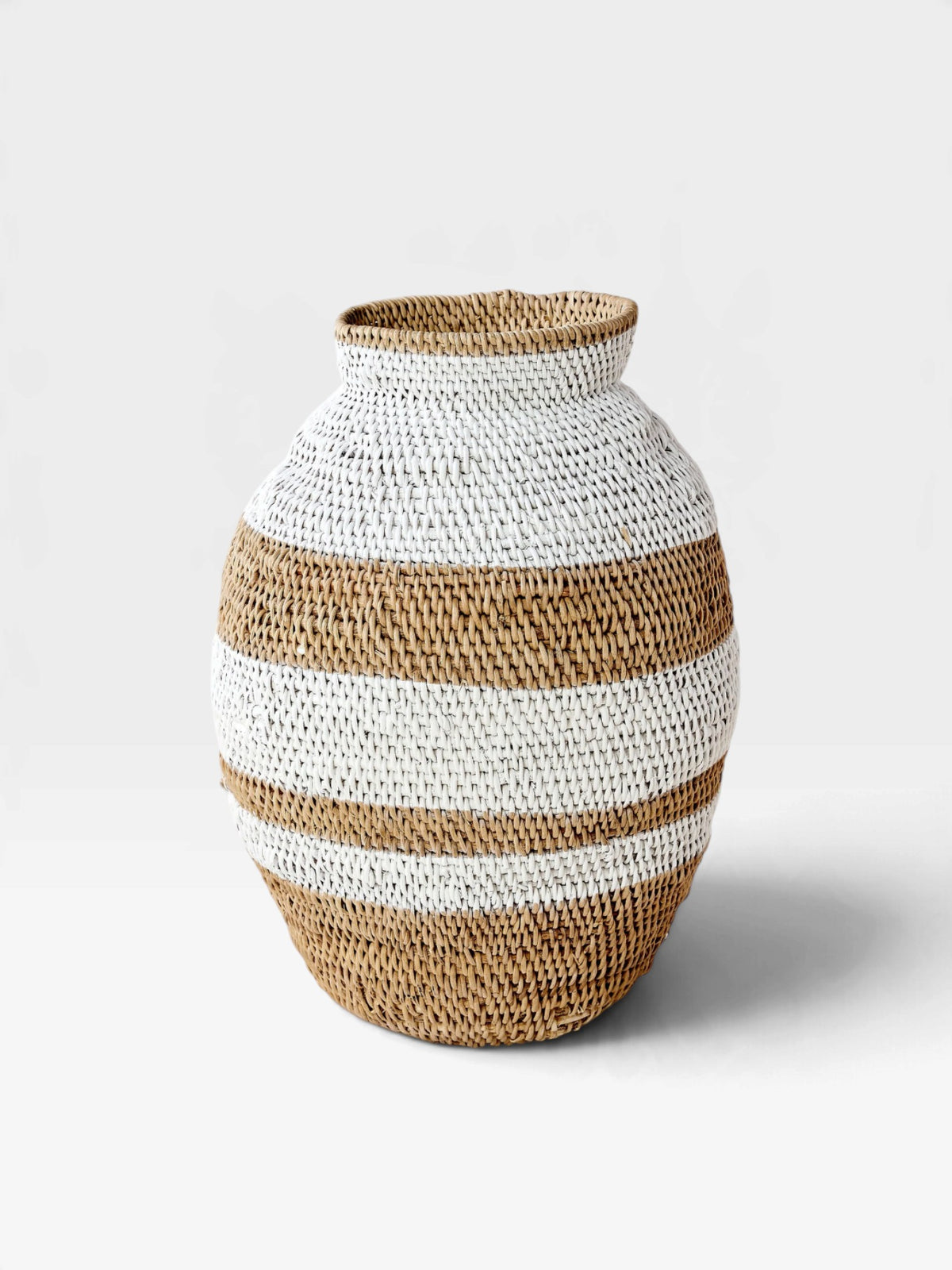 A hand-woven basket vase with horizontal stripes of natural tan and off-white, photographed on a clean white background.