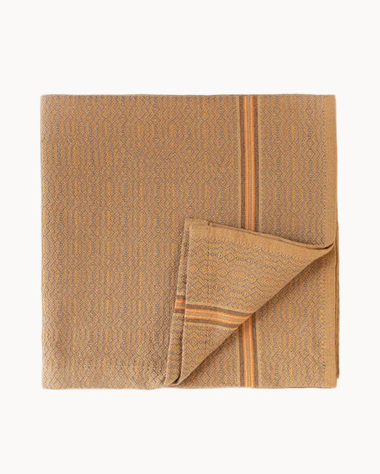A folded kitchen towel in a goldenrod color with accents of orange and gray, featuring a subtle diamond pattern and a single stripe set on a white background.