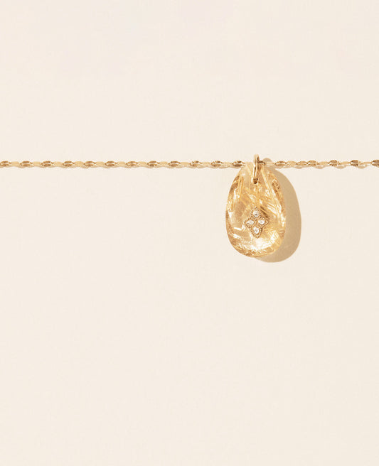 Segment of a twisted gold chain necklace with a subtly tear-drop shaped rutile quartz pendant with a diamond and gold inlay featured in the center.