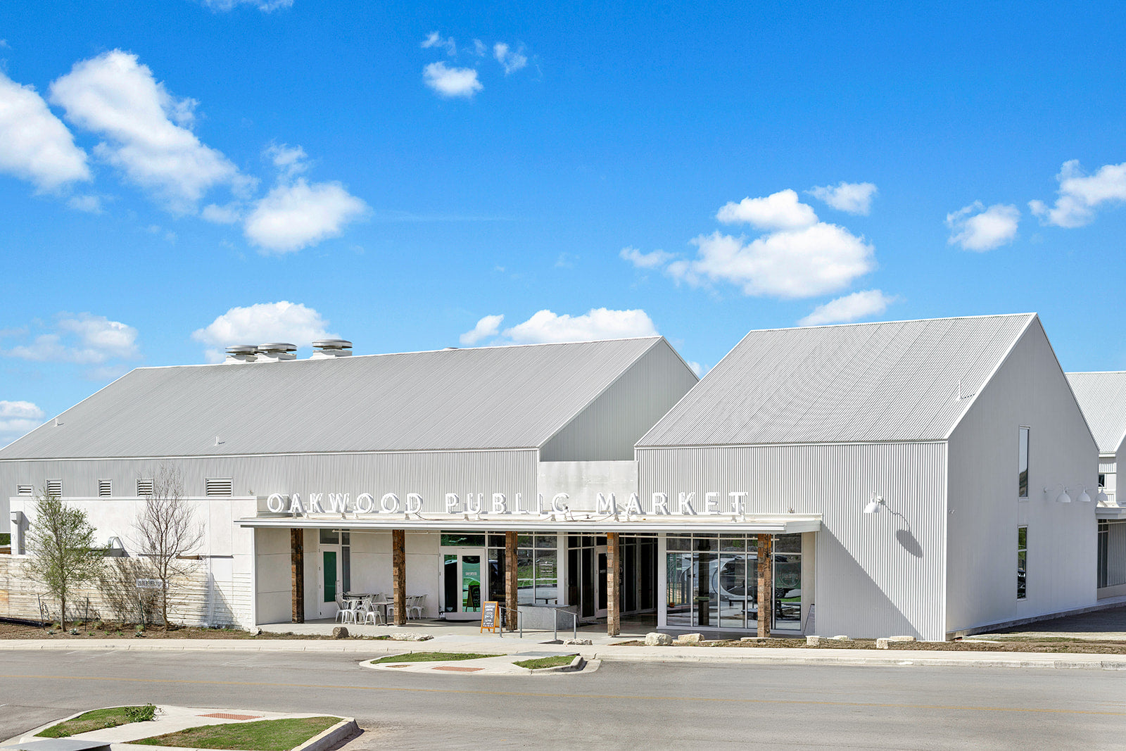 Modern building with a gray roof and white walls under a blue sky with clouds.