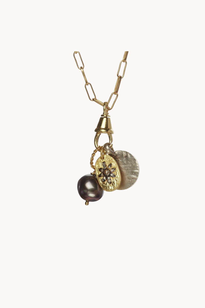 Gold necklace with gold and black pearl pendants on a soft white background