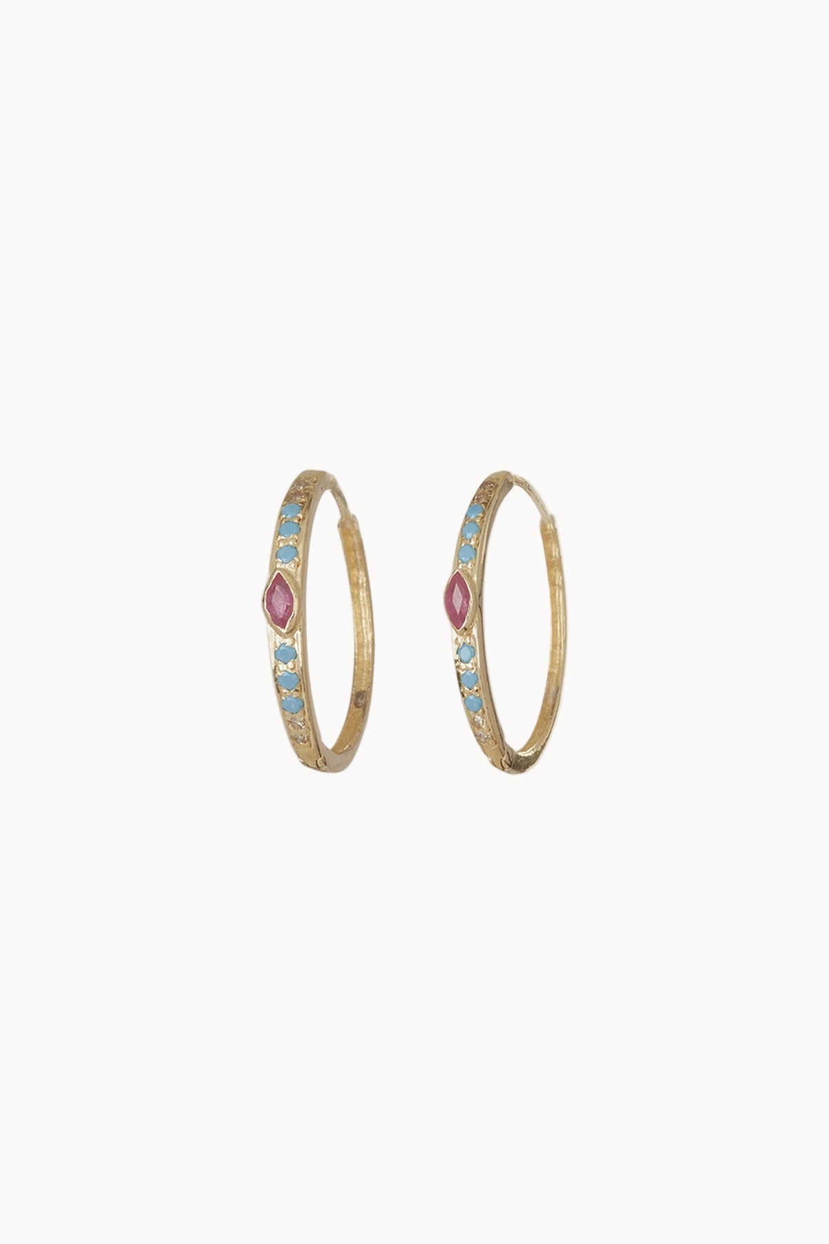 A pair of gold hoop earrings with inlaid diamonds, turquoise and ruby sitting against a soft white background