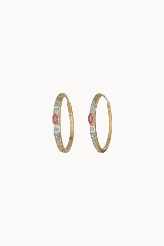 A pair of gold hoop earrings with inlaid diamonds, turquoise and ruby sitting against a soft white background