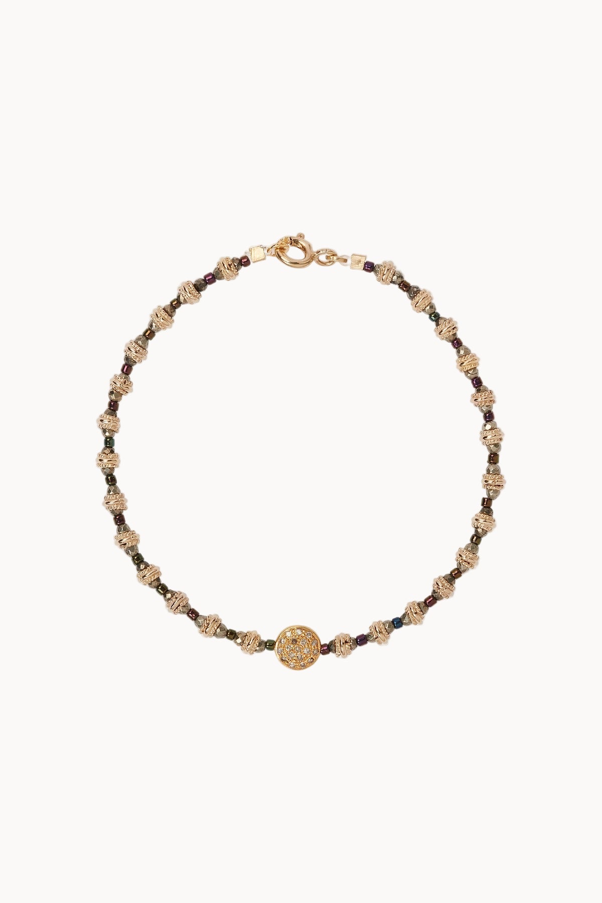 Bracelet with gold bead detailing sitting against a soft white background