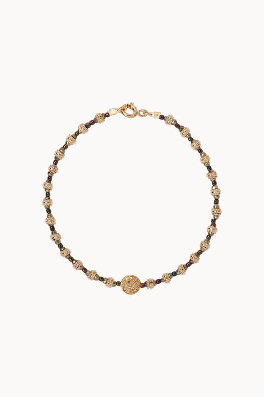 Bracelet with gold bead detailing sitting against a soft white background