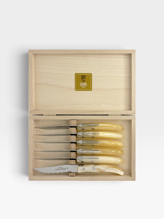 A set of 6 knives with marbled ivory resin handles displayed in a wooden box set on a white background