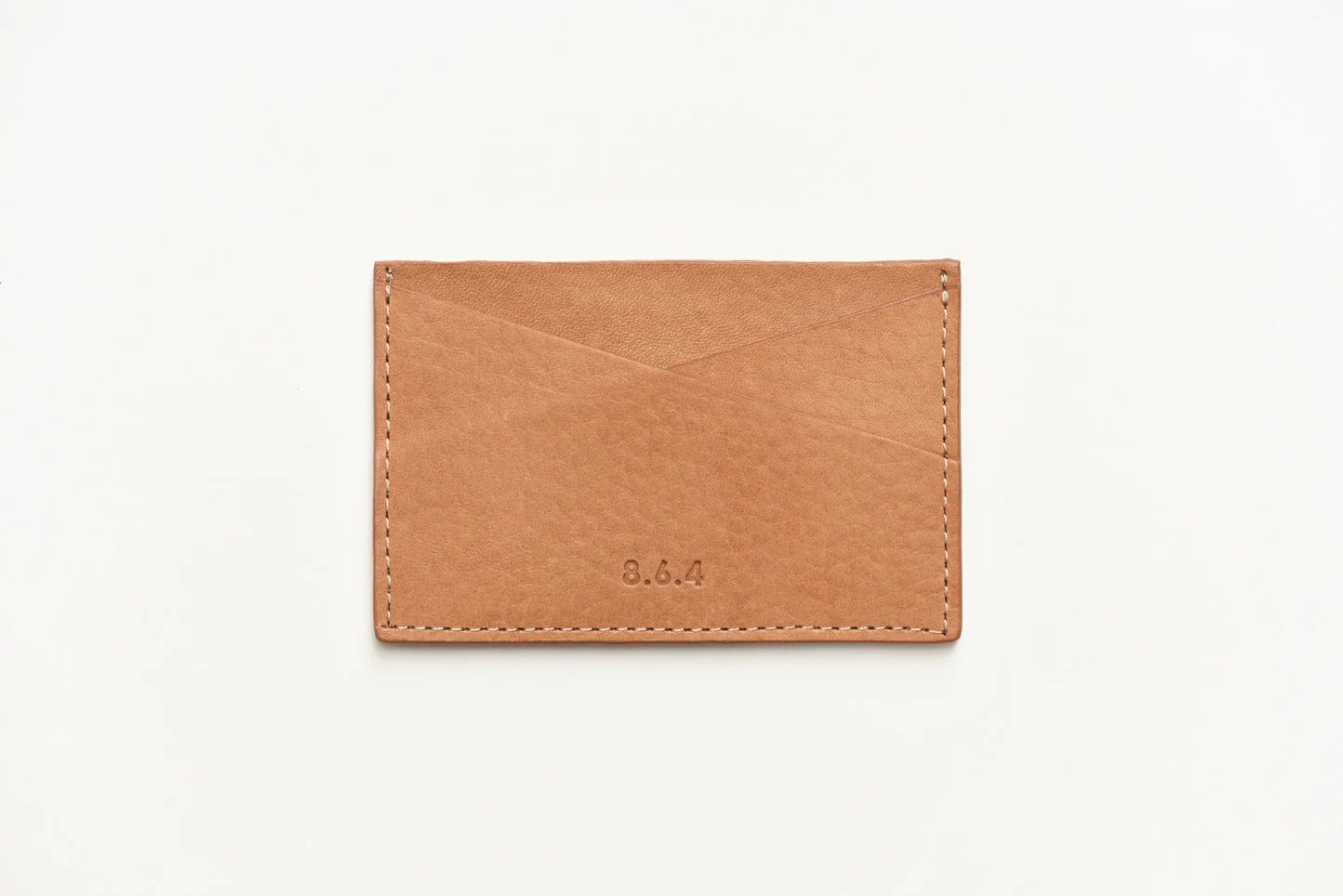 Tan-colored pebbled leather cardholder on a white background