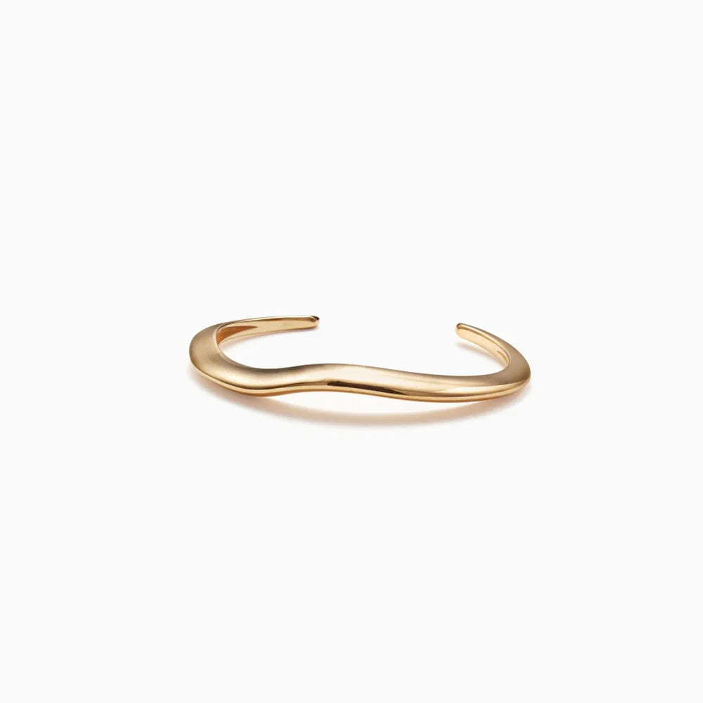 Curved gold cuff bracelet on a white background