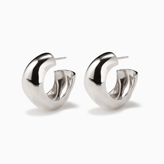 Pair of chunky, irregular-shaped silver hoop earrings on a white background
