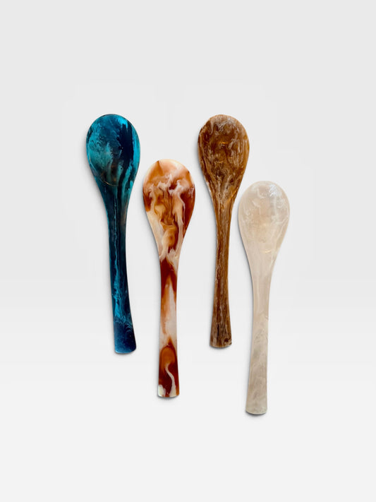 Four marbled resin salad server spoons in colors of teal, black, red, white, brown, and white set against a white background.