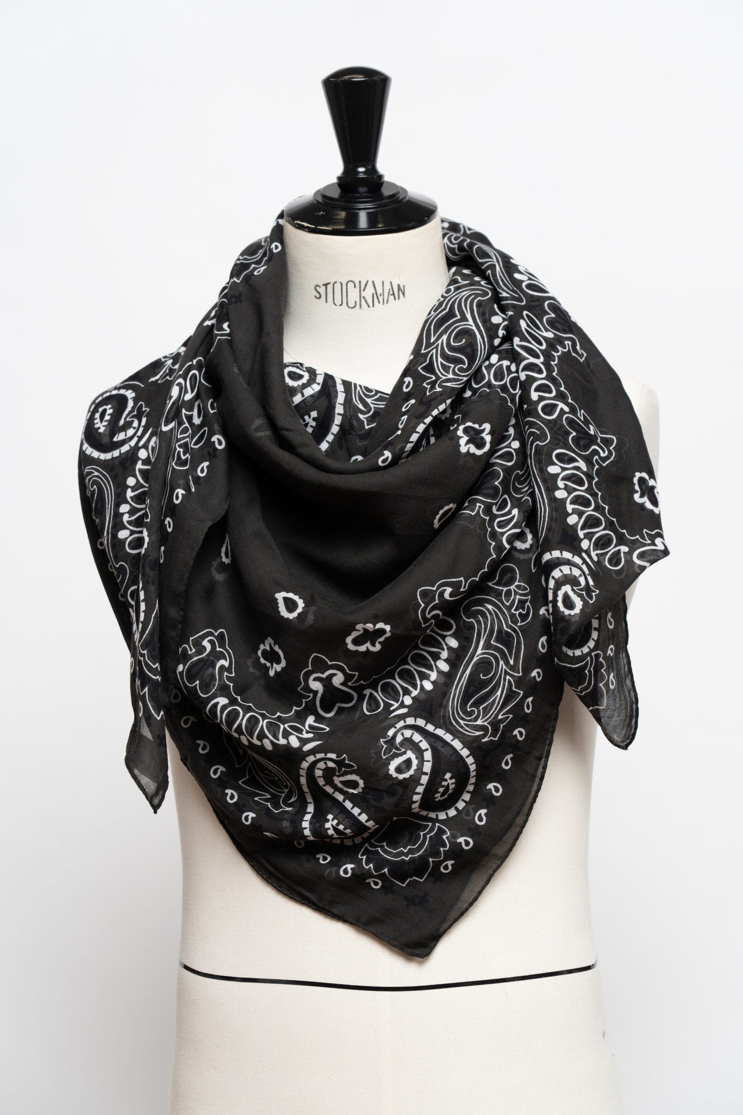 Black bandana with white patterns draped over a mannequin on a white background