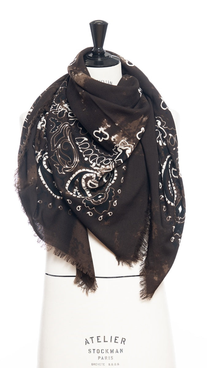 A deep brown scarf with a white bandana motif design draped around a mannequin bust set against a white background.
