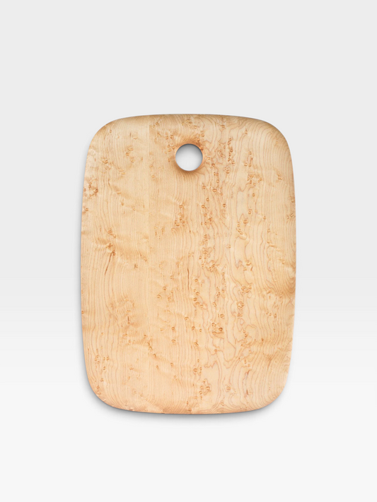 A rectangular wooden cutting board with rounded corners and a circular hole near the top, featuring a prominent natural burl wood grain pattern in light tan and beige tones, set against a clean white background.