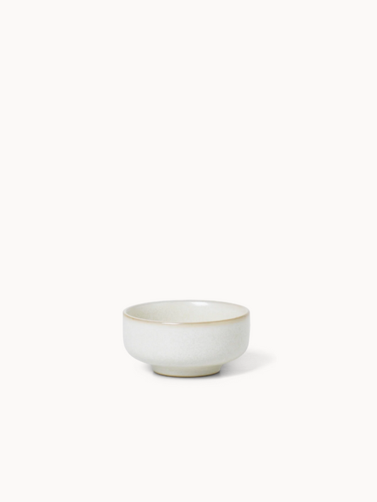 Small white ceramic salt bowl with gold rim on a white background