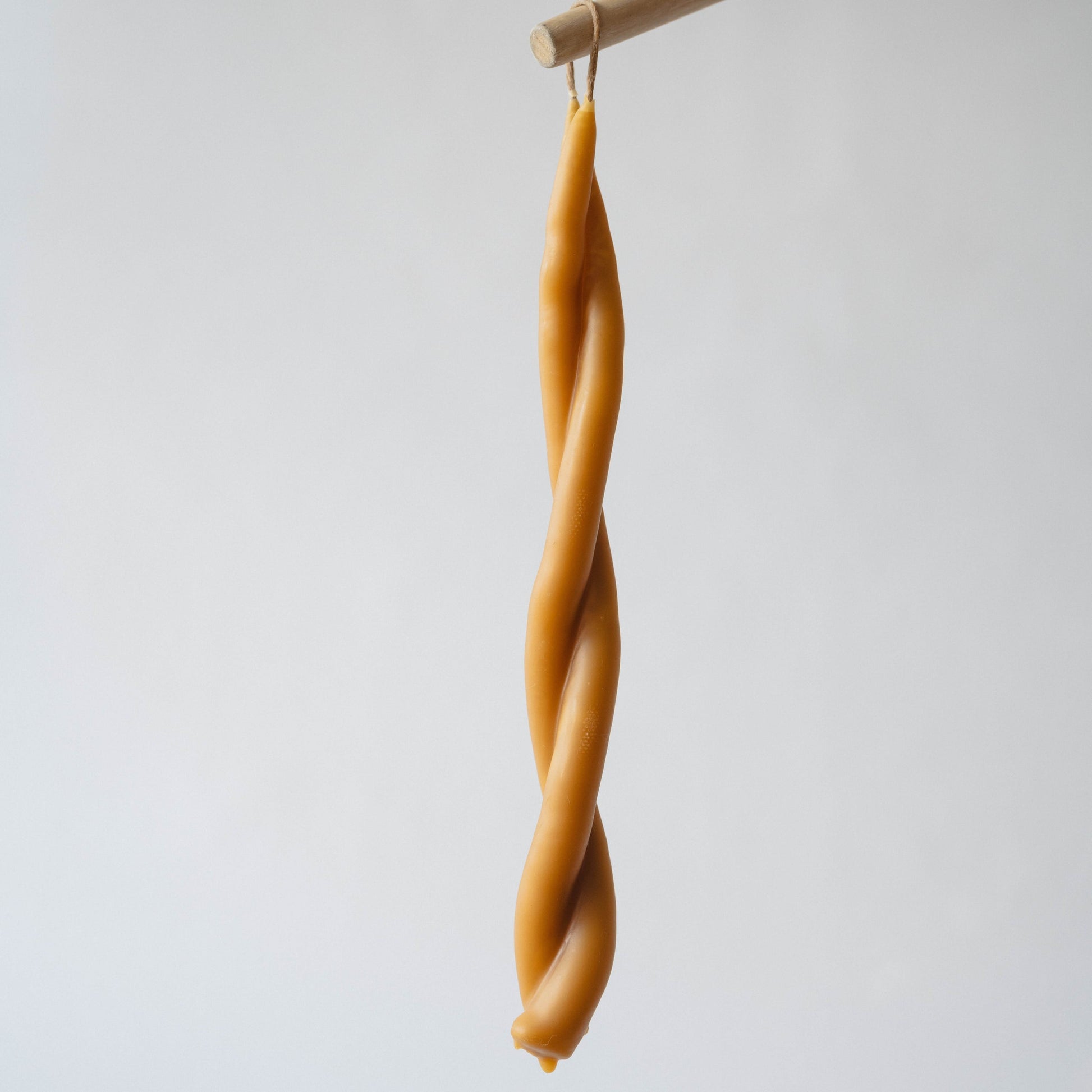 A twisted taper candle made of beeswax, displayed against a neutral background.